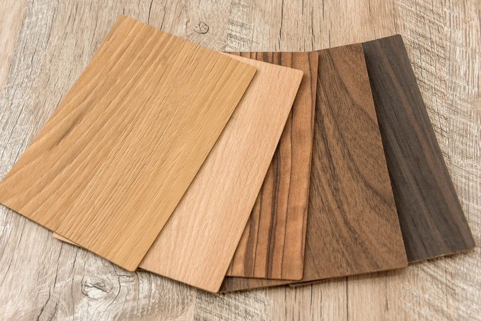 Homme en tenue de travail installant du parquet dans une pièce en rénovation, agenouillé sur le sol, utilisant un marteau pour ajuster les lames de bois