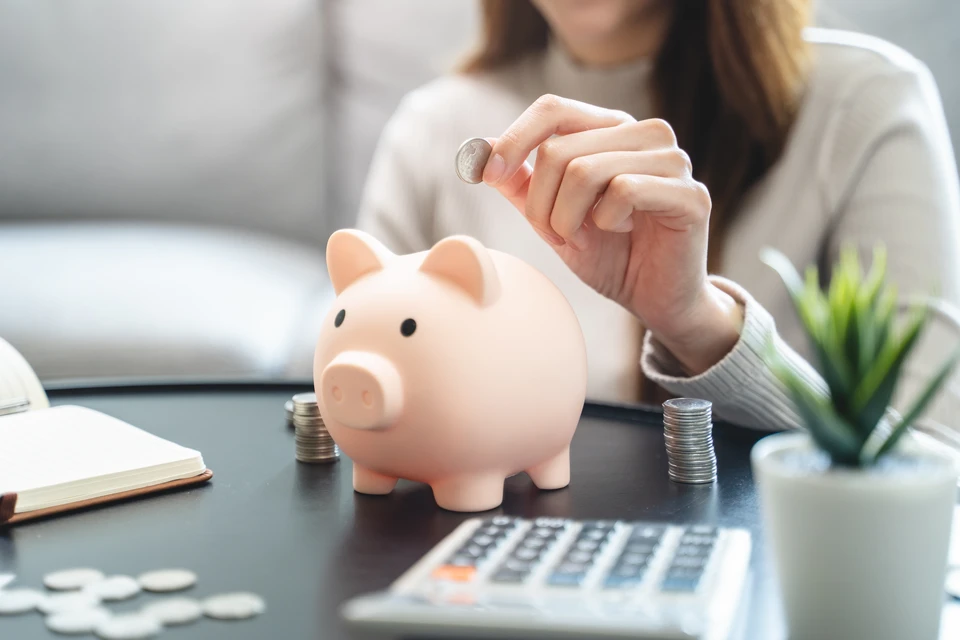 Gros plan d'une main tenant un crayon au-dessus d'un devis détaillé ou d'un document de budget, posé sur un bureau avec calculatrice, le tout dans un environnement professionnel lumineux. L'image doit transmettre la confiance, la clarté et la maîtrise financière d'un projet de rénovation.