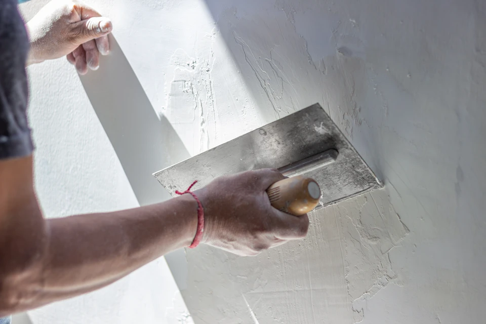 Artisan à genoux installe un parquet en lames de bois sur chantier intérieur