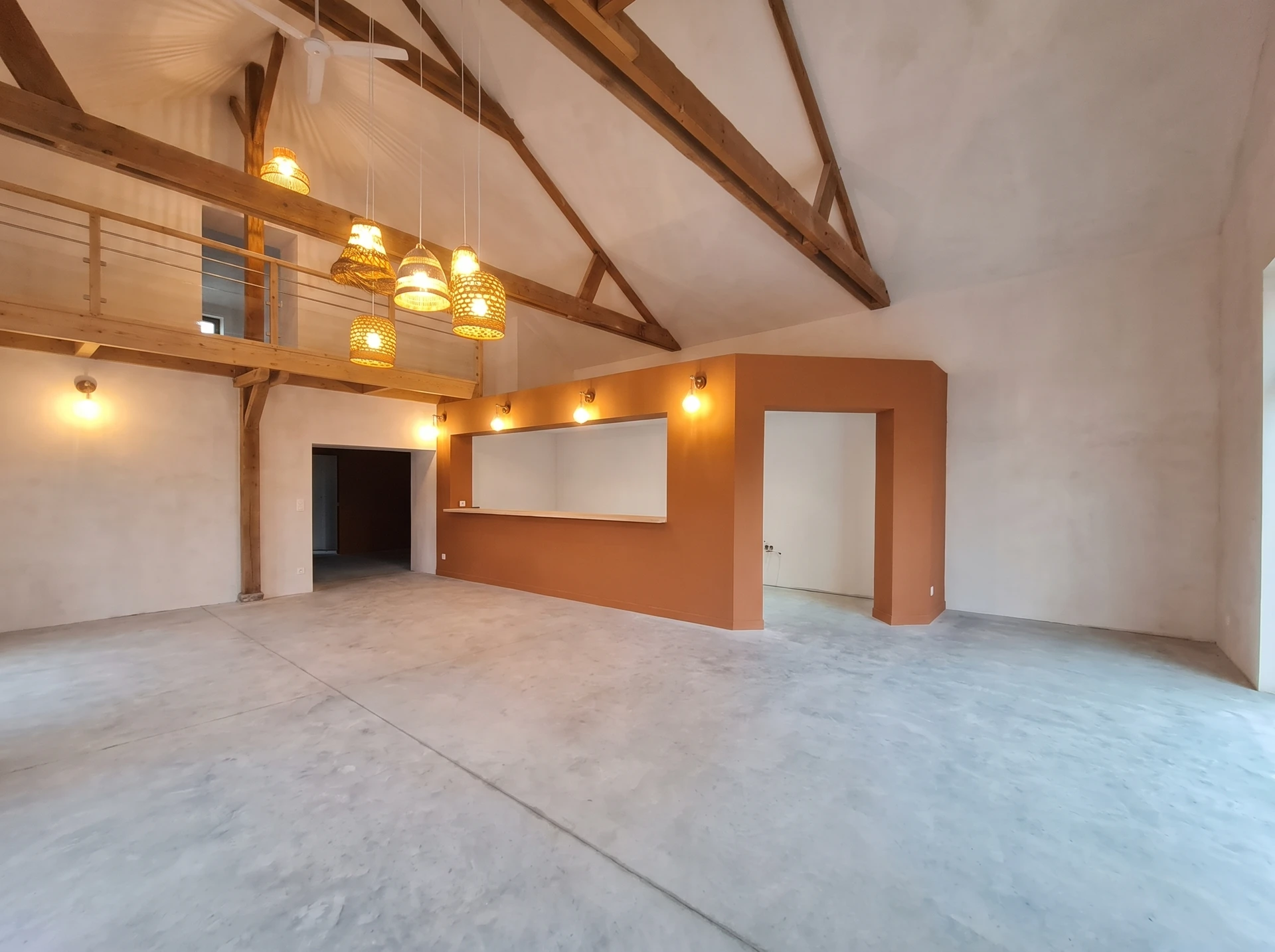 Espace intérieur en cours de rénovation avec murs en béton brut et cloison à lames de bois verticales