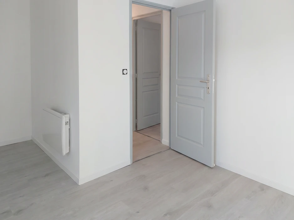 Pièce vide rénovée avec murs blancs et parquet stratifié gris clair