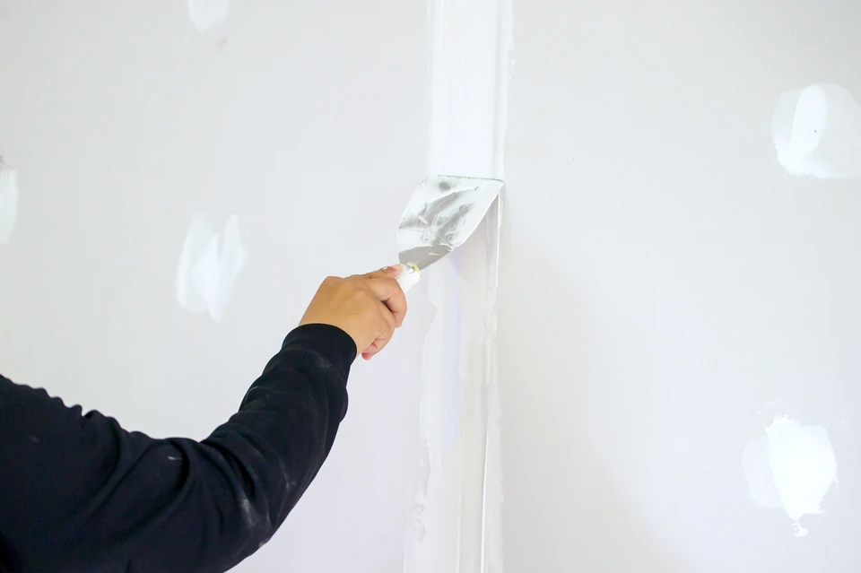 un ouvrier en maçonnerie fait un mur de béton par bloc de ciment et un plâtre sur le chantier