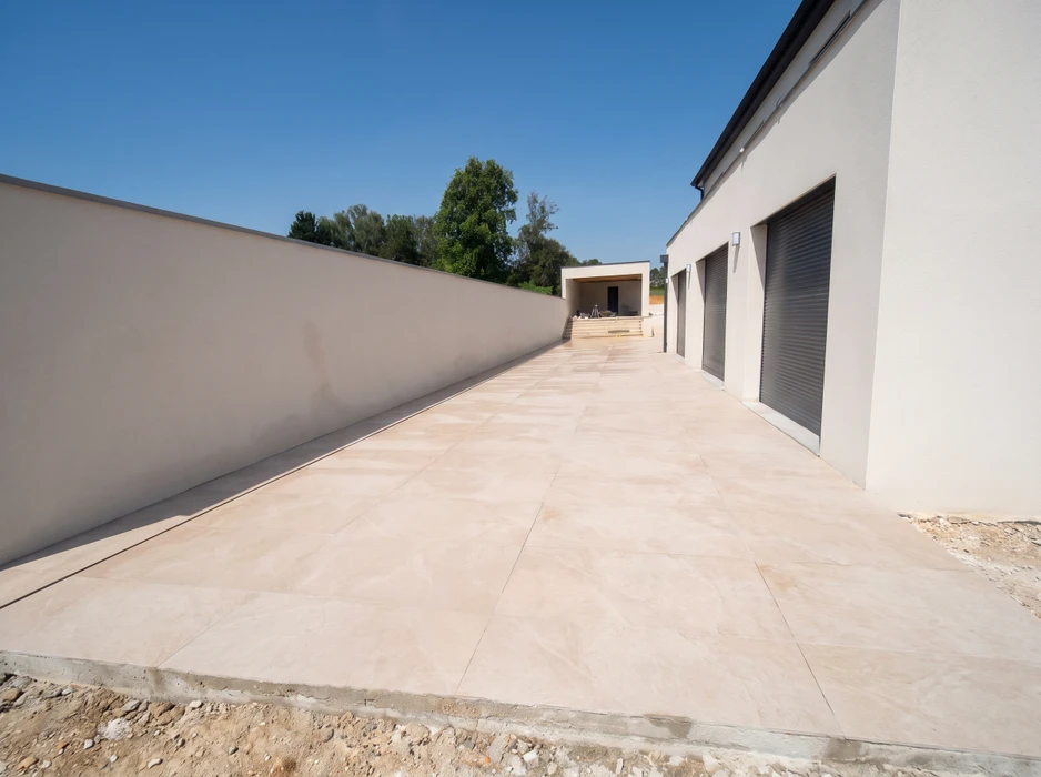 Allée extérieure d'une villa contemporaine, dallage en grès cérame grand format beige sable, pose en calepinage régulier
