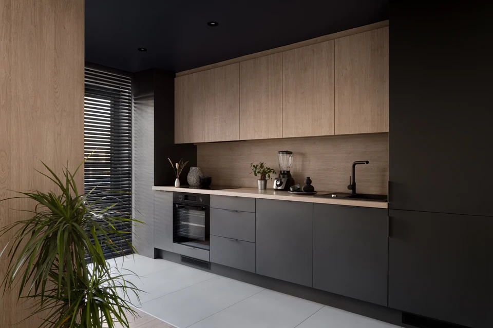 Cuisine moderne équipée avec plan de travail intégré, four encastrable avec porte vitrée, plaques de cuisson quatre feux, tiroirs de rangement, lave-vaisselle intégré