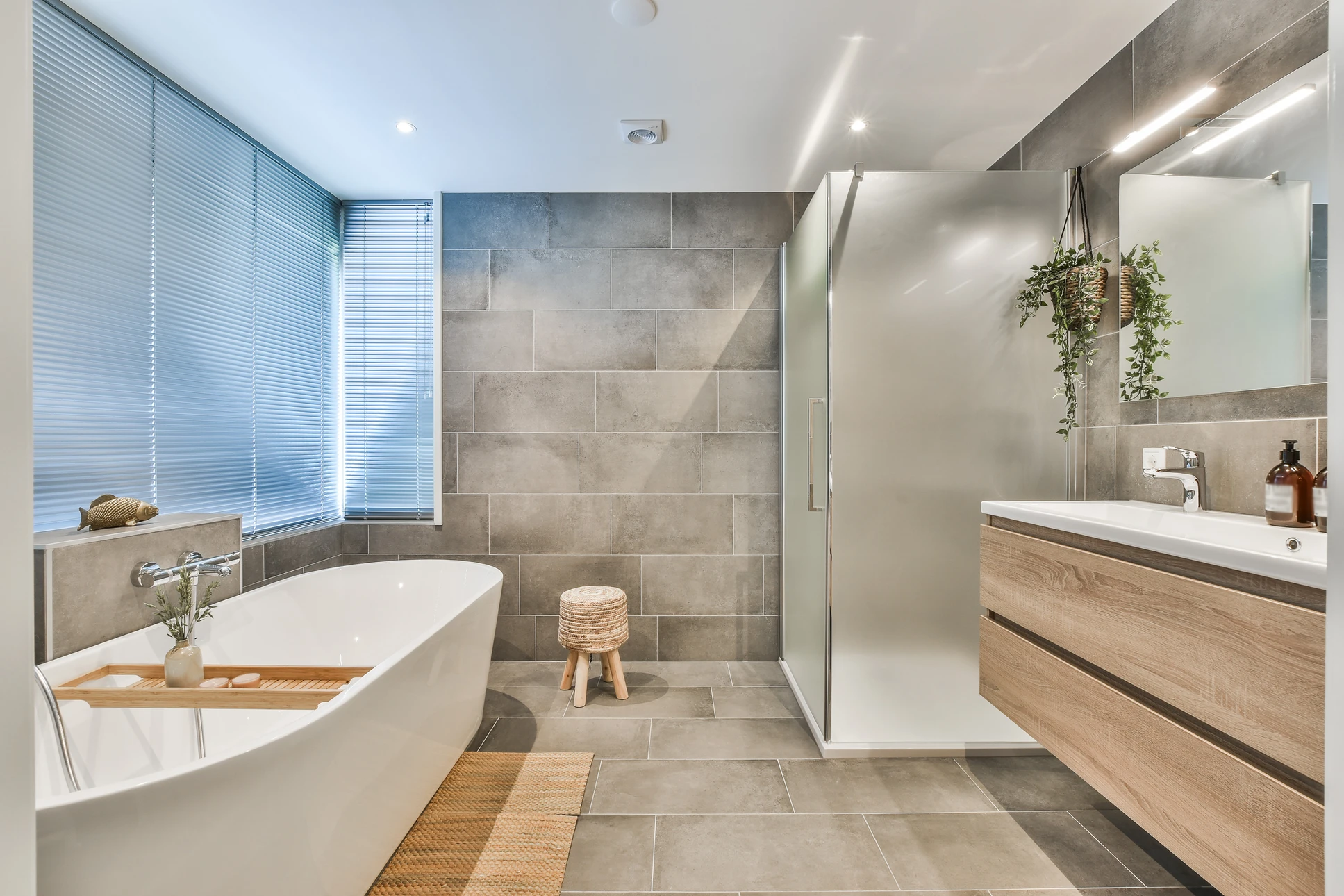 Salle de bain moderne avec douche à l'italienne, carrelage blanc et gris, receveur de douche carrelé, paroi de douche en verre, colonne de douche thermostatique