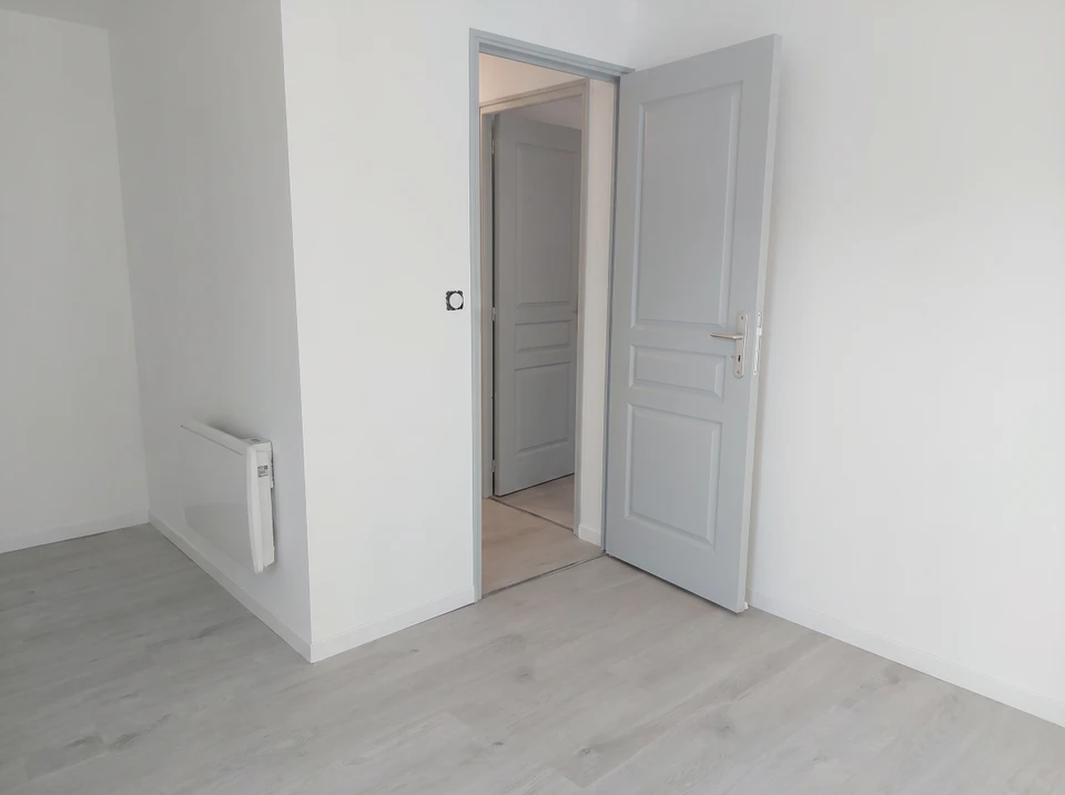 Pièce vide rénovée avec murs blancs et parquet stratifié gris clair