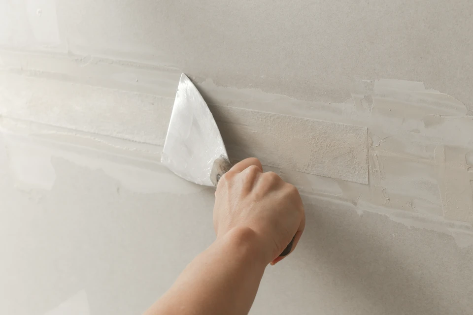 un ouvrier en maçonnerie fait un mur de béton par bloc de ciment et un plâtre sur le chantier