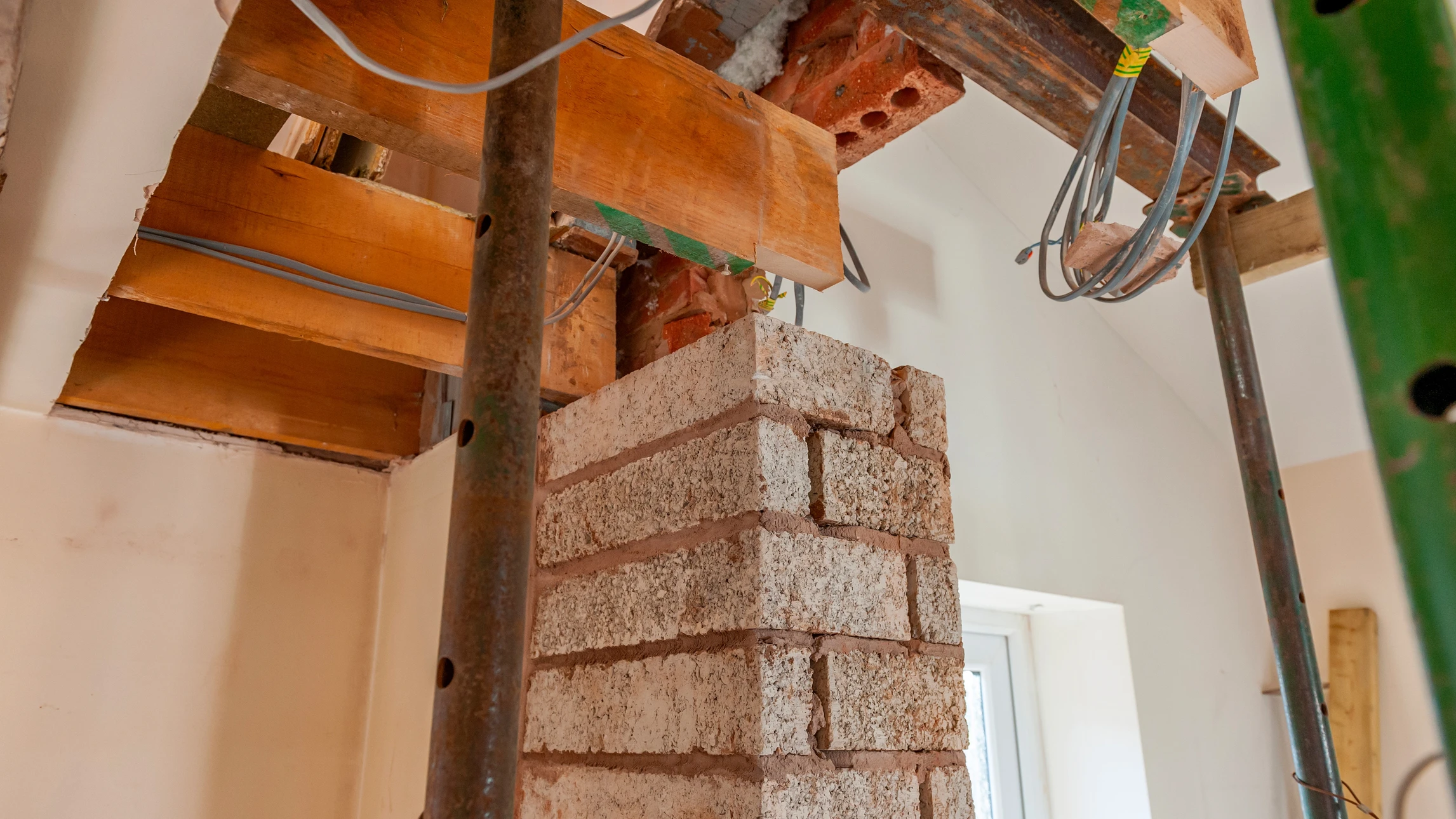 Intérieur d'une pièce principale en cours ou après rénovation, mettant en avant la transformation : murs fraîchement revêtus en placo lisse et blancs, sol nouvellement recouvert de carrelage ou parquet, cloisons créées délimitant les espaces. Vue d'ensemble montrant la diversité des travaux de finition intérieure (placo, sol, revêtements). Angle de vue légèrement surélevé, lumière naturelle mettant en avant la qualité et la propreté du chantier rénové. Aucun personnage visible.